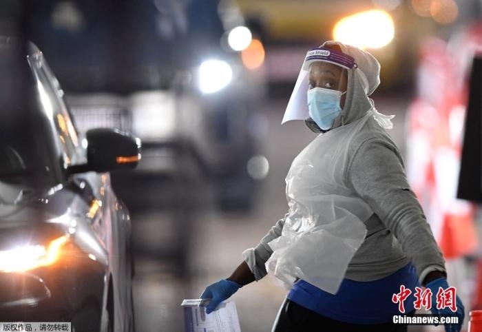 當(dāng)?shù)貢r間12月18日，英國政府公布的數(shù)據(jù)顯示，當(dāng)天英國新增奧密克戎毒株感染病例10059例。鑒于奧密克戎毒株感染病例激增，住院人數(shù)不斷上升，倫敦市長宣布倫敦進(jìn)入“重大事故”狀態(tài)。圖為倫敦的一個免下車檢測中心，一名醫(yī)務(wù)工作者正準(zhǔn)備對司機進(jìn)行核酸檢測。