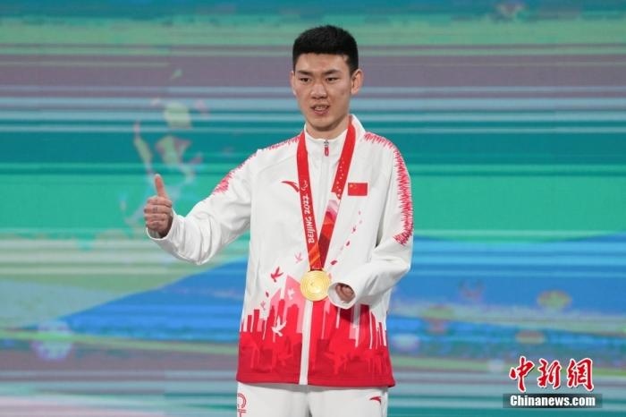 3月6日，梁景怡在延慶頒獎(jiǎng)廣場(chǎng)領(lǐng)獎(jiǎng)臺(tái)上豎起大拇指。當(dāng)日，在國(guó)家高山滑雪中心舉行的北京2022年冬殘奧會(huì)殘奧高山滑雪男子超級(jí)大回轉(zhuǎn)—站姿決賽中，中國(guó)選手梁景怡奪得冠軍。 <a target='_blank' href='/'>中新社</a>記者 楊華峰 攝