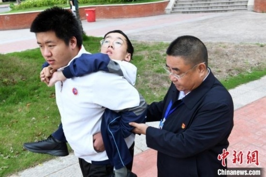 朱金祥背著鐘華強(qiáng)去教室上課的路上，也經(jīng)常碰到值班的校領(lǐng)導(dǎo)和老師前來搭把手。 卓忠偉 攝