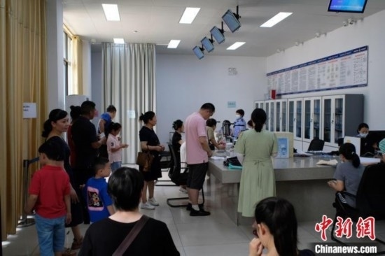 圖為在戶籍辦證廳內(nèi)排隊(duì)等待的家長(zhǎng)和孩子。劉俊聰 攝