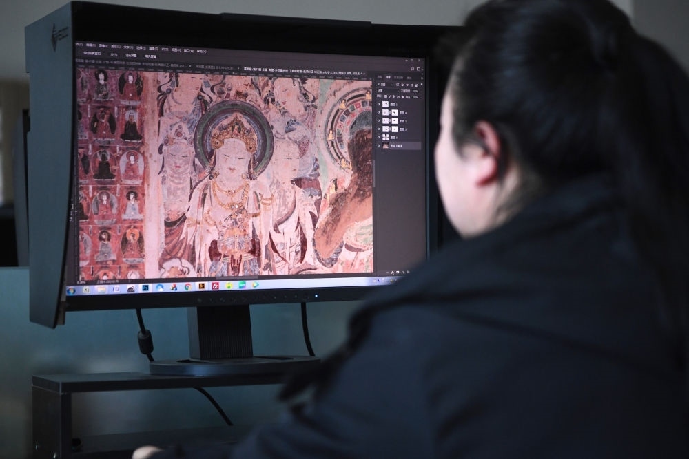 敦煌研究院文物數(shù)字化保護(hù)團(tuán)隊(duì)圖像處理人員年海麗在拼接壁畫圖像（2023年4月25日攝）。數(shù)字化探索為莫高窟的保護(hù)與傳承開辟了全新路徑，數(shù)字技術(shù)讓敦煌文物走出洞窟，跨出國(guó)門，走向“永久保存、永續(xù)利用”。新華社記者 陳斌 攝