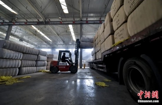 新疆喀什綜合保稅區(qū)，喀什啟路國(guó)際貿(mào)易有限公司的倉(cāng)庫(kù)內(nèi)，工人正在裝載從塔吉克斯坦和烏茲別克斯坦進(jìn)口的棉花。劉新攝
