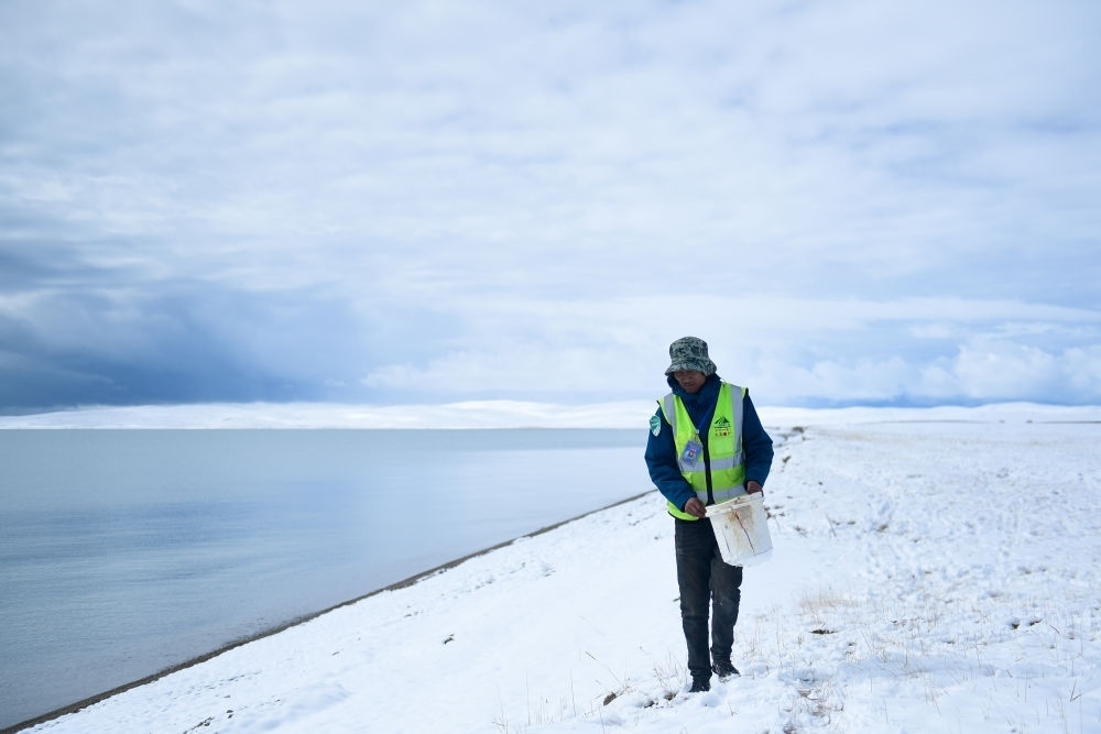 2021年10月20日，在青海省果洛藏族自治州瑪多縣扎陵湖鄉(xiāng)勒那村，三江源國(guó)家公園黃河源園區(qū)生態(tài)管護(hù)員在扎陵湖邊撿拾垃圾。新華社記者 張龍 攝
