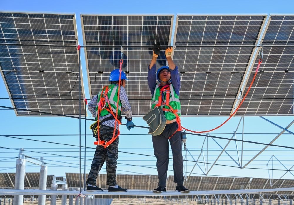 2023年7月22日，工人在位于內(nèi)蒙古杭錦旗庫(kù)布其沙漠億利生態(tài)示范區(qū)的蒙西基地庫(kù)布其200萬(wàn)千瓦光伏治沙項(xiàng)目工地安裝光伏板。新華社記者 劉磊 攝