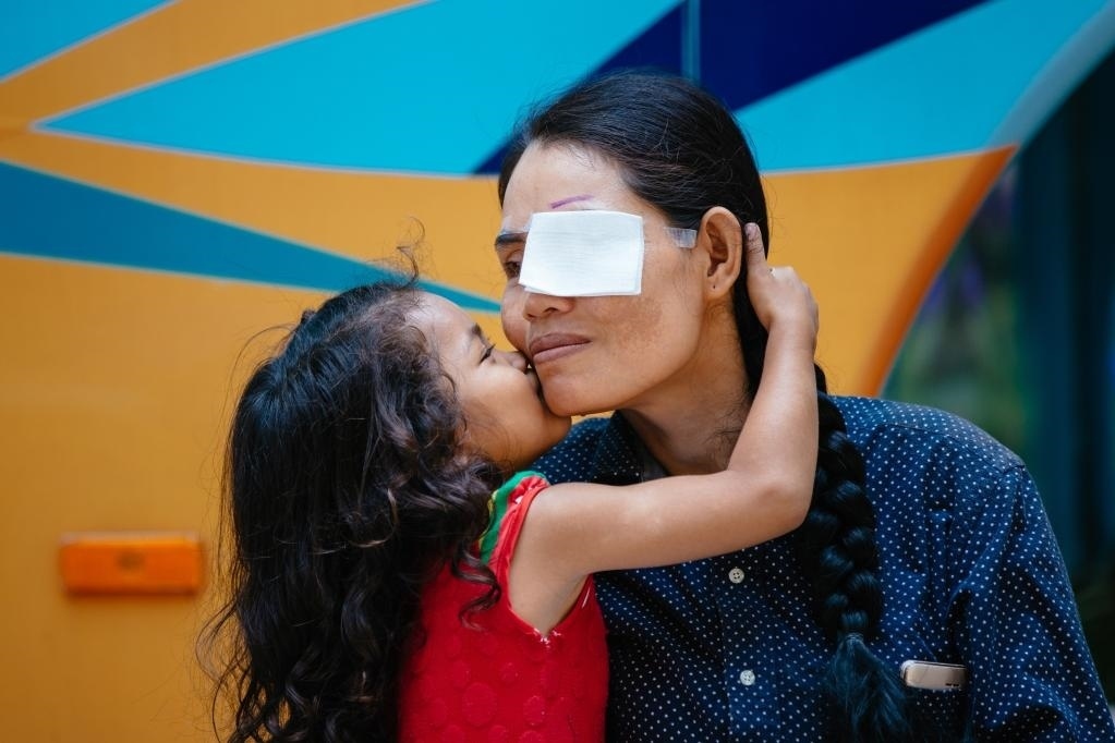 2019年3月15日，在柬埔寨磅湛省醫(yī)院，即將接受白內(nèi)障手術(shù)的患者孫美樂接受女兒的親吻祝福。在接受了中國醫(yī)療隊的白內(nèi)障義診手術(shù)后，她的視力逐步恢復(fù)，生活有了新的光明和希望。