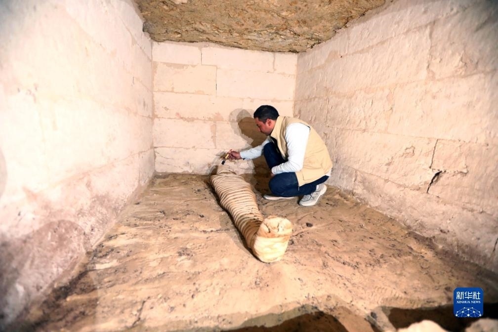 10月15日，在埃及明亞省考古現(xiàn)場(chǎng)，考古人員清理一座石鑿墓中的木乃伊。新華社發(fā)（艾哈邁德·戈馬攝）