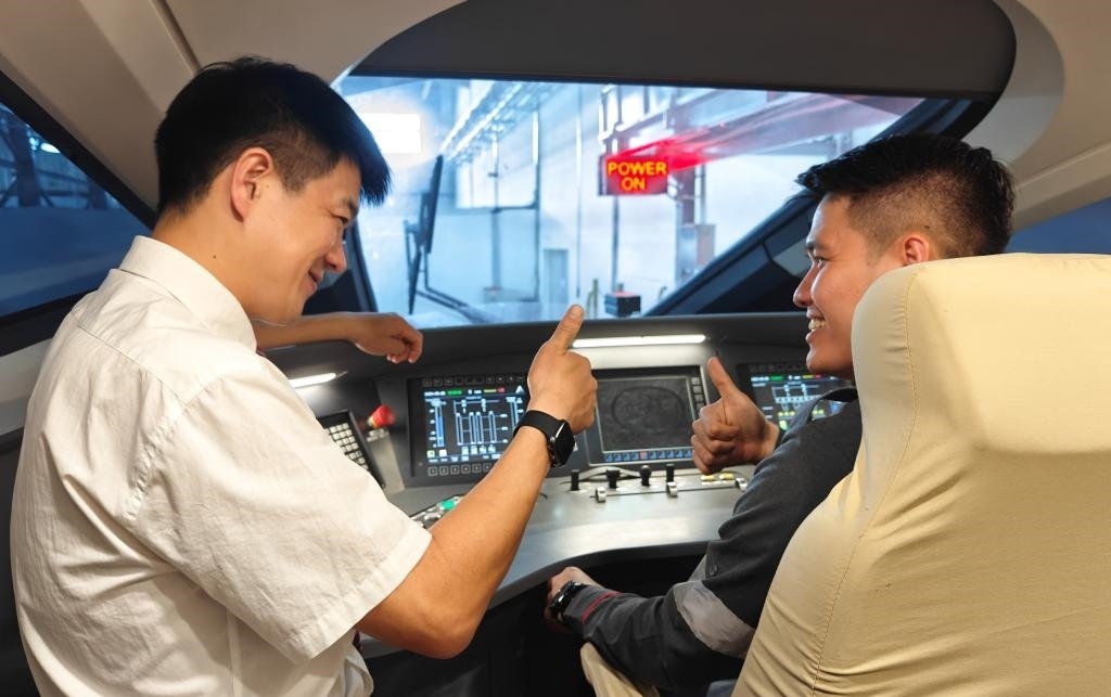 8月25日，在印度尼西亞萬隆的雅萬高鐵德卡魯爾動車所內(nèi)，中國師傅穆振（左）在向印尼火車司機塞蒂亞萬講解動車組出庫前的上電作業(yè)。