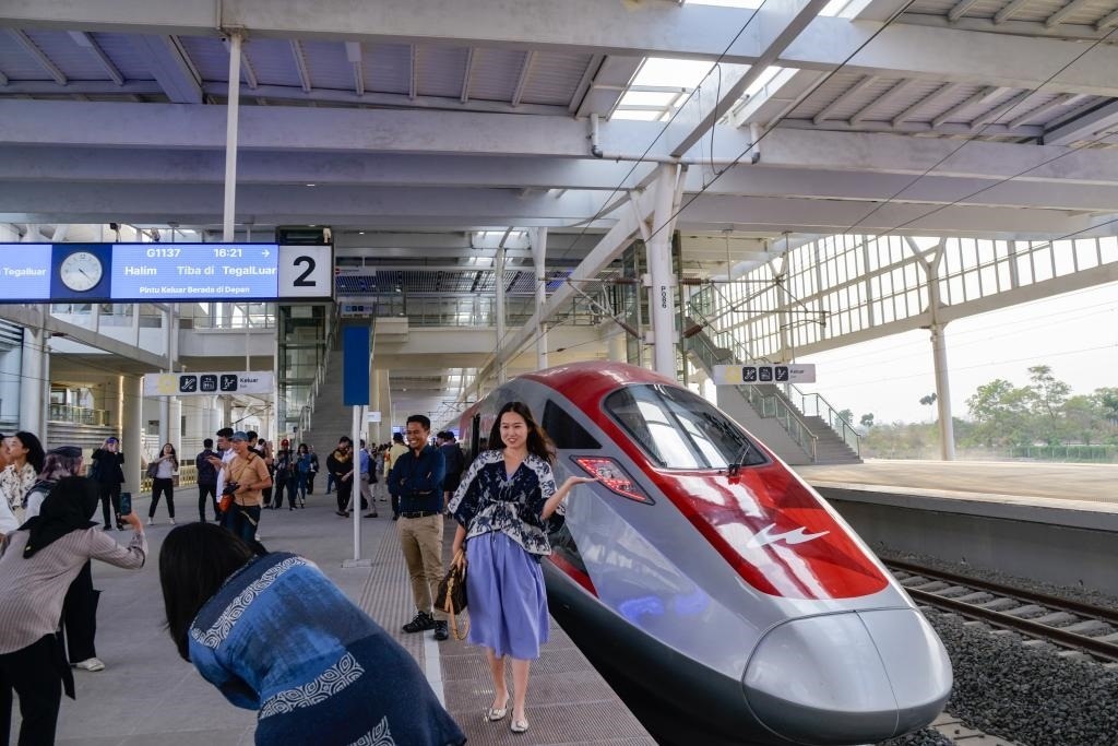 10月17日，在印度尼西亞萬隆德卡魯爾站，乘客在站臺上和雅萬高鐵高速動車組列車合影。