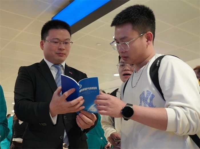 工作人員（左一）在發(fā)放《中國領事保護與協(xié)助指南》。 中國駐迪拜總領事館供圖