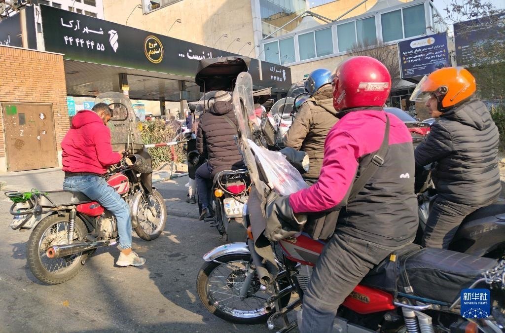 12月18日，摩托車在伊朗首都德黑蘭的一家加油站外等待加油。新華社記者 沙達提 攝