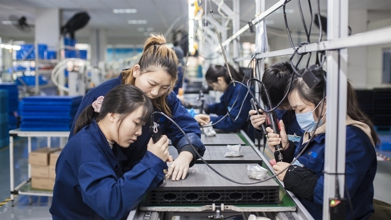 在新亞勝光電的產(chǎn)品線上，工人正進行產(chǎn)品組建和安裝布線。受訪者供圖