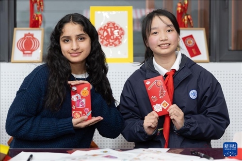 1月28日，美國(guó)馬斯卡廷中學(xué)學(xué)生（左）和復(fù)旦大學(xué)第二附屬學(xué)校學(xué)生展示互相送出的寫有寄語(yǔ)祝福的紅包。 新華社記者 王翔 攝