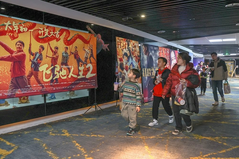△ 2024年2月16日，在江西贛州一家電影院，觀眾從春節(jié)檔電影的宣傳展板前走過。