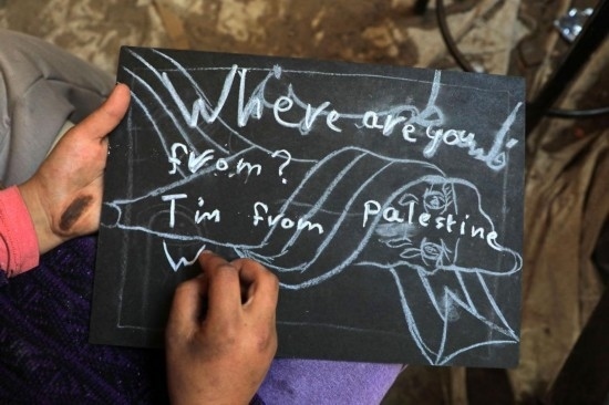 2023年12月28日，一名學(xué)生在加沙地帶南部城市拉法一所學(xué)校的臨時(shí)教室中寫下“我來自巴勒斯坦”的字樣。新華社發(fā)（里澤克·阿卜杜勒賈瓦德攝）