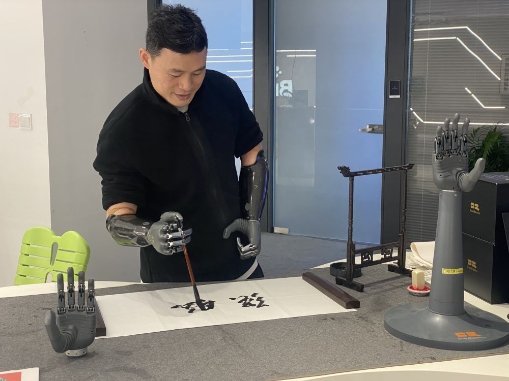 2024年3月29日，在浙江強(qiáng)腦科技有限公司展廳內(nèi)，失去雙手的產(chǎn)品體驗(yàn)官倪敏成依靠智能仿生手寫毛筆字。新華社記者 魏一駿 攝