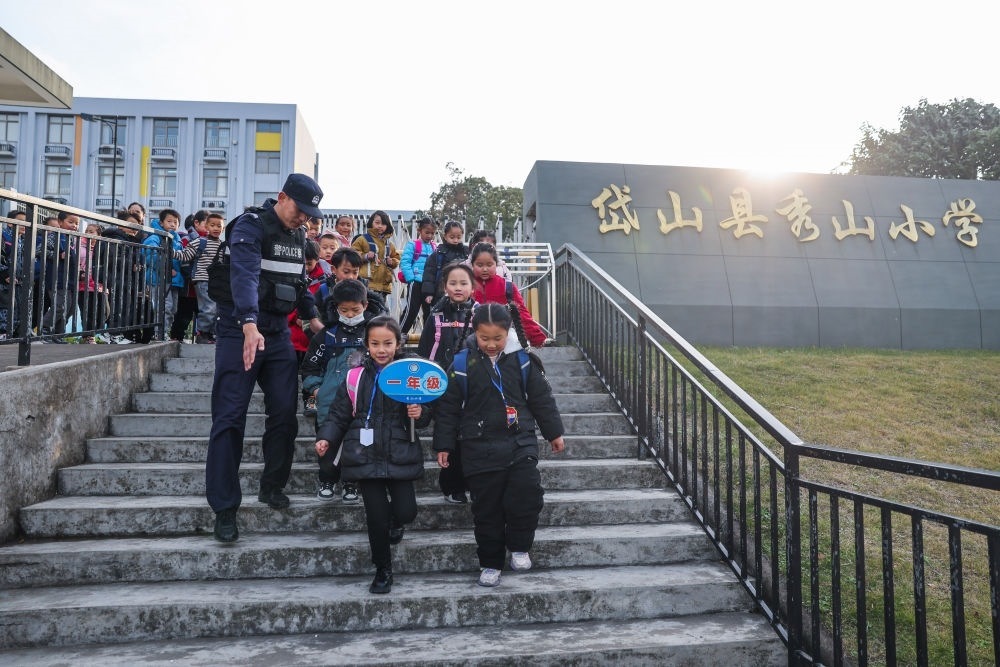 2023年12月20日，秀山派出所民警在秀山小學(xué)放學(xué)時(shí)間參與“護(hù)學(xué)崗”維持秩序，同時(shí)接獨(dú)自放學(xué)的學(xué)生去“民生小鋪”。浙江省舟山市岱山縣公安局秀山派出所聯(lián)合鄉(xiāng)鎮(zhèn)、社區(qū)成立“民生小鋪”，為當(dāng)?shù)鼐用?、外?lái)務(wù)工人員及其子女等服務(wù)，協(xié)助解決外來(lái)務(wù)工人員在工作、生活等方面的矛盾和問(wèn)題，助力鄉(xiāng)鎮(zhèn)基層治理。新華社記者 徐昱 攝