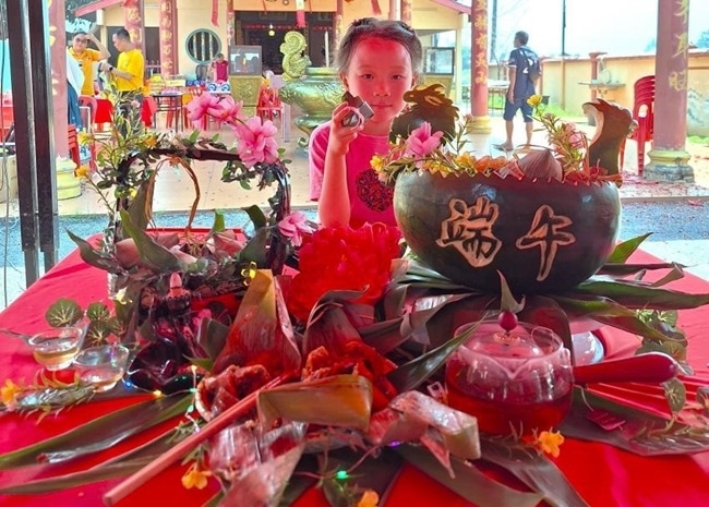 小朋友展示學(xué)裹粽子的成品照。組委會供圖