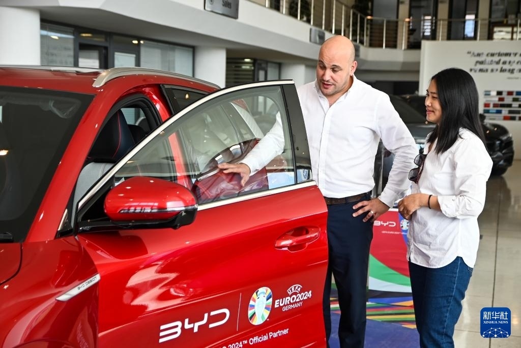 2024年5月29日，在馬耳他比爾基卡拉，馬耳他哈桑-扎米特汽車公司首席執(zhí)行官德古阿拉（左）介紹一輛比亞迪純電動汽車。新華社發(fā)（喬納森·博格 攝）