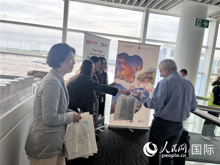 圖為工作人員向乘客發(fā)放復(fù)航首班禮物。 牛瑞飛攝