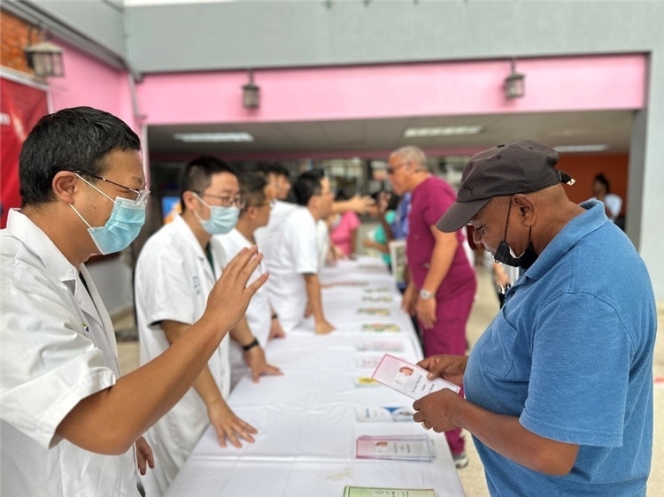 援圭醫(yī)療隊隊員們在啟動儀式上為當(dāng)?shù)孛癖姺职l(fā)宣傳手冊。中國援助圭亞那醫(yī)療隊供圖