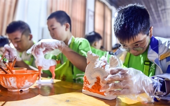 小朋友們?cè)诼尻?yáng)市孟津區(qū)朝陽(yáng)鎮(zhèn)南石山村體驗(yàn)唐三彩素胎施釉技藝。圖片來(lái)源：視覺(jué)中國(guó)