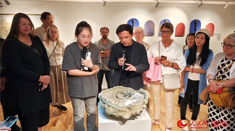 參展人、景德鎮(zhèn)陶瓷大學(xué)設(shè)計(jì)藝術(shù)學(xué)院副院長(zhǎng)余劍峰（中）向來(lái)賓介紹參展作品。人民網(wǎng)記者 殷淼攝