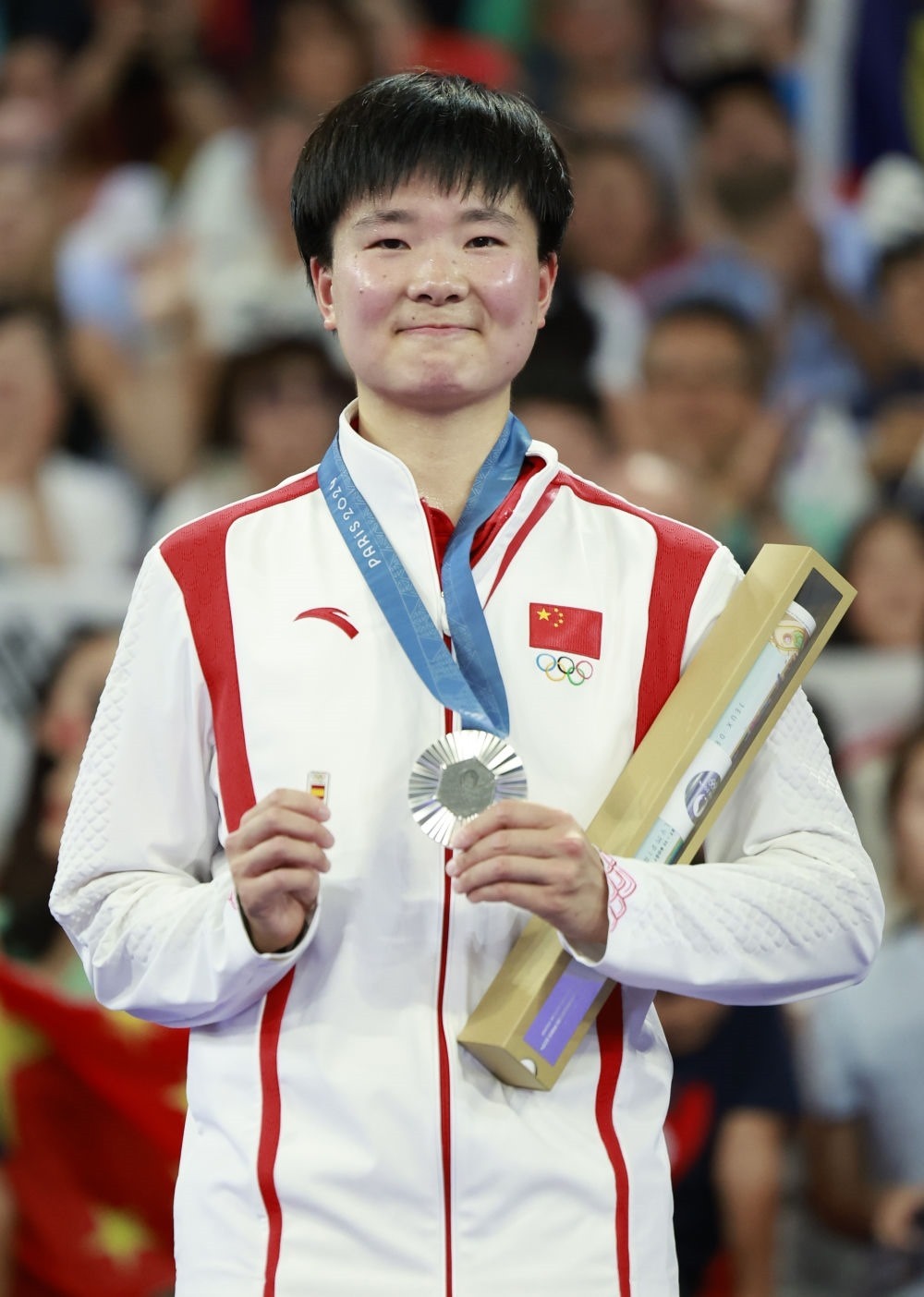 巴黎奧運(yùn)會(huì)羽毛球女子單打亞軍、中國(guó)選手何冰嬌在頒獎(jiǎng)儀式上一手握著銀牌，一手握著西班牙奧委會(huì)徽章（2024年8月5日攝）。新華社記者 任正來(lái) 攝