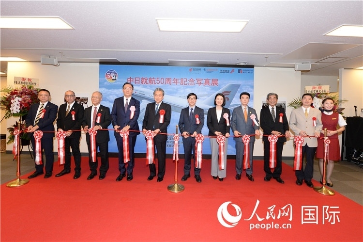 與會(huì)嘉賓共同為中日通航50周年紀(jì)念圖片展開幕剪彩。馮學(xué)敏攝
