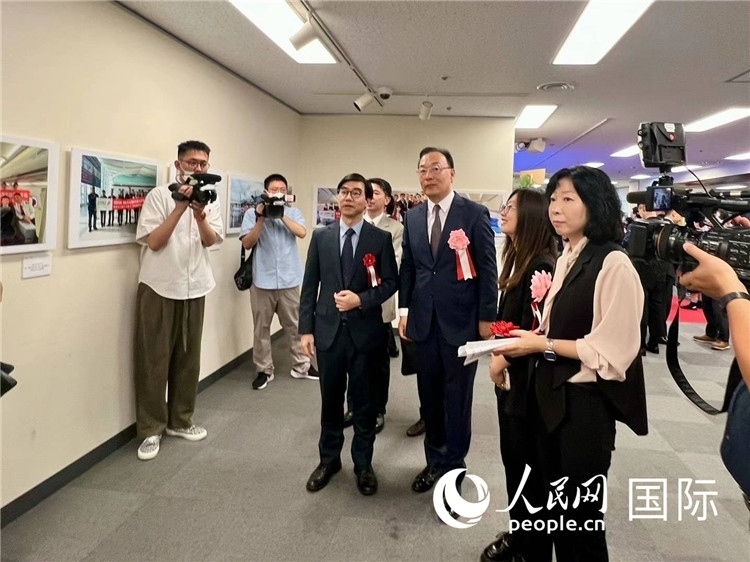 中國(guó)國(guó)際航空日韓地區(qū)支社支社長(zhǎng)馮力為中國(guó)駐日本大使館臨時(shí)代辦施泳等嘉賓介紹展出圖片。人民網(wǎng) 許可攝