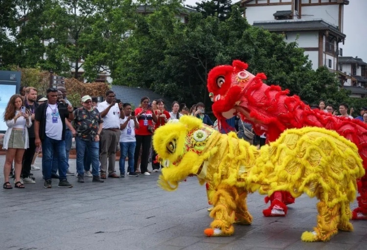 2024“一帶一路”媒體合作論壇聯(lián)合采訪調(diào)研行成員在樂(lè)山蘇稽古鎮(zhèn)觀看非遺舞獅表演。本報(bào)記者 伊霄攝