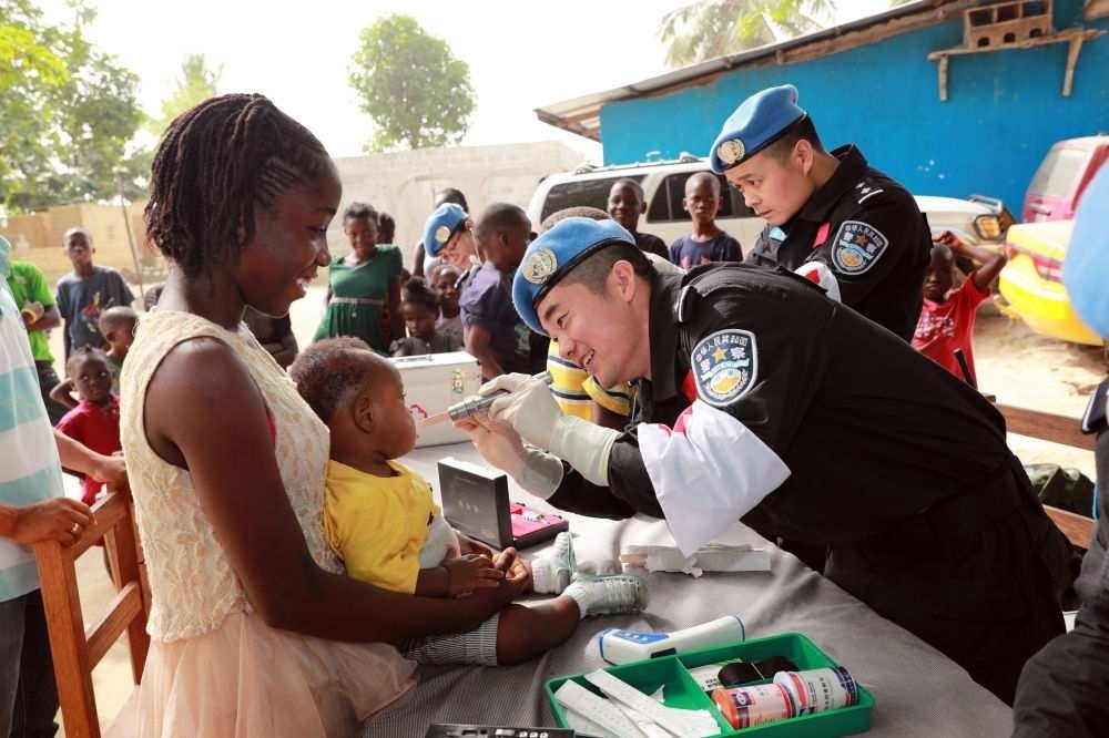 2017年12月28日，在利比里亞蒙羅維亞，中國維和警察防暴隊醫(yī)療人員為兒童做口腔檢查。