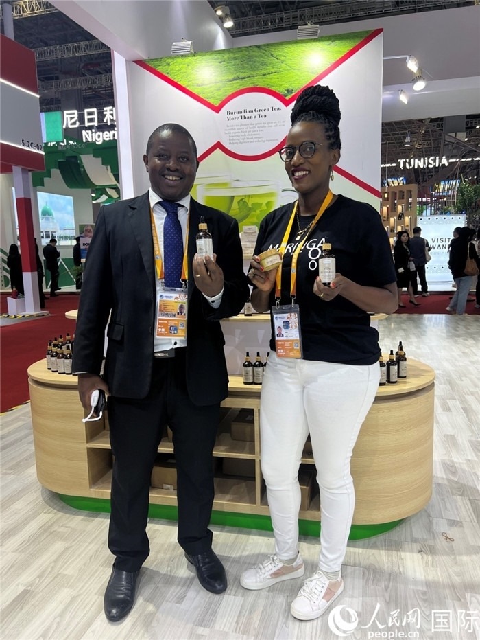 6月6日，布隆迪駐華大使館一等參贊布利馬索·阿爾弗雷德 (左，Bulimaso Alfred) 和參展商卡馬里扎·埃斯特拉 (Kamariza Estella) 在第七屆中國(guó)國(guó)際進(jìn)口博覽會(huì)布隆迪館展示當(dāng)?shù)厣a(chǎn)的辣木油。（人民網(wǎng) 艾里士 攝）