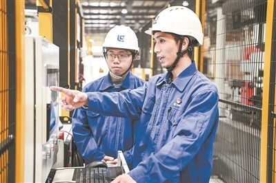 在廣西柳工機械股份有限公司生產(chǎn)車間內(nèi)，一名高級技師（右）給徒弟講解數(shù)控設(shè)備操作細節(jié)。新華社記者 曹祎銘攝