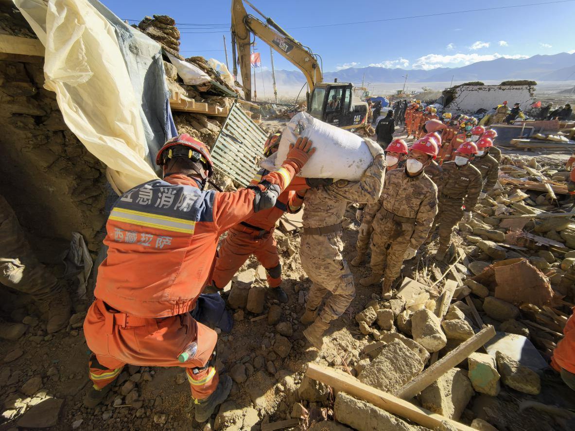 1月11日，定日縣長(zhǎng)所鄉(xiāng)古榮村，應(yīng)急消防等救援人員排隊(duì)接力搶運(yùn)掩埋在倒塌房屋下的群眾財(cái)物。人民日?qǐng)?bào)記者楊翹楚攝