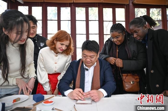 1月20日，篆刻家王臻向外籍留學(xué)生展示篆刻印章。當日，來自巴西、馬來西亞、加納、哈薩克斯坦的外籍留學(xué)生在浙江杭州西泠印社體驗福貼、春聯(lián)和篆刻，感受古老的中國傳統(tǒng)文化。中新社記者 王剛 攝