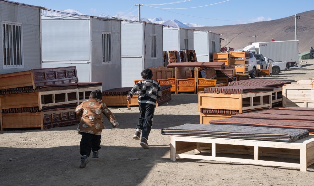 2025年1月13日，在定日縣嘎旦村，兩個孩子在剛運(yùn)來的兩排藏床間奔跑。新華社記者丁增尼達(dá) 攝