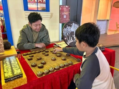 柯秋楓與市民下椰雕象棋。人民網(wǎng) 陳葉欣攝