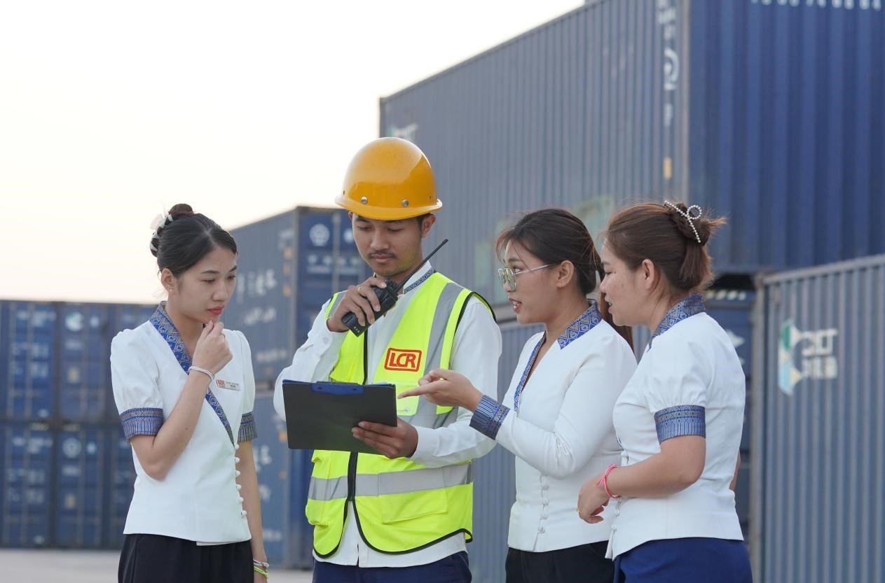 萬象南站貨運值班員陳尼啦（左一）與同事在一起討論工作。老中鐵路有限公司供圖