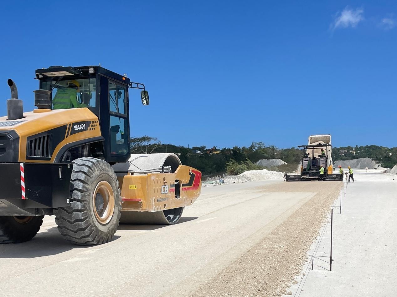 圖為中企承建的牙買加蒙特哥貝繞城路項(xiàng)目基層試驗(yàn)段正在進(jìn)行攤鋪和碾壓施工，相關(guān)施工工作已于日前順利完成。中國(guó)港灣美洲區(qū)域公司供圖