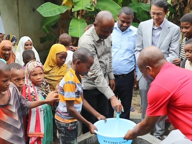 在日前舉行的安全供水工程揭牌儀式上，當(dāng)?shù)匦∨笥言诠┧c接水。 施亮攝