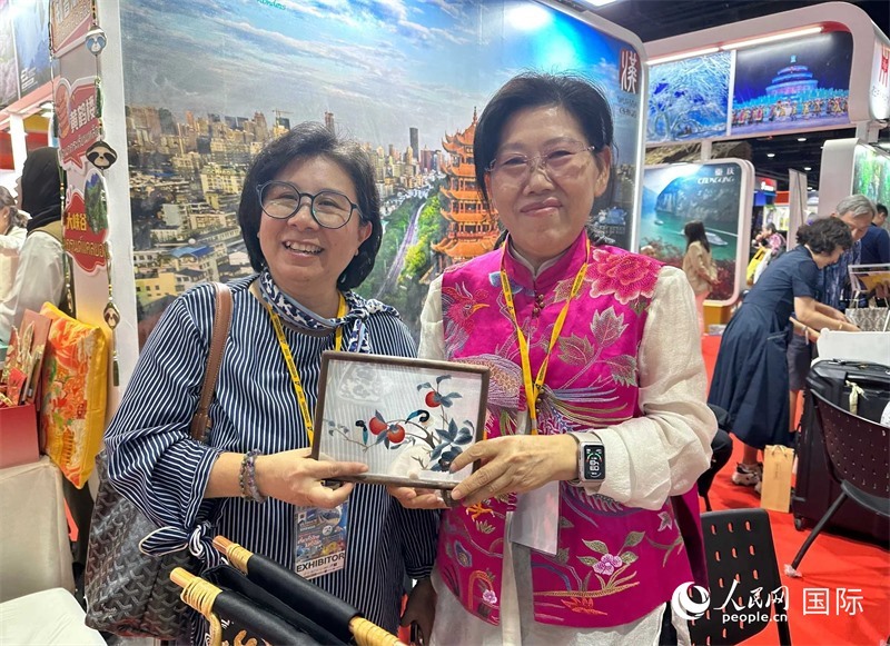 中國“大冶刺繡”傳承人劉小紅（右）參加泰國國際旅游展，向觀眾介紹中國非遺刺繡針法。人民網(wǎng)記者 簡承淵攝