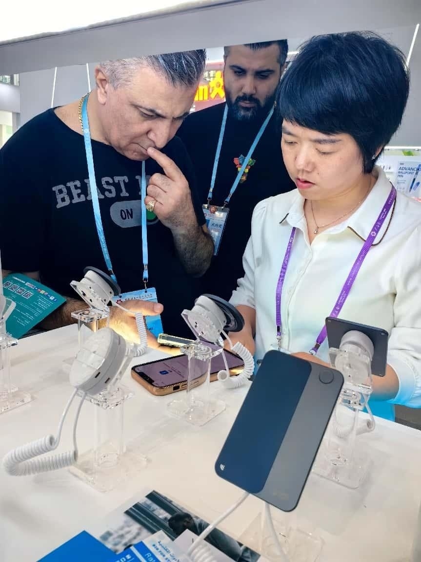 展臺(tái)工作人員向外商展示“AI TOP翻譯終端”。圖片來(lái)源：受訪者提供