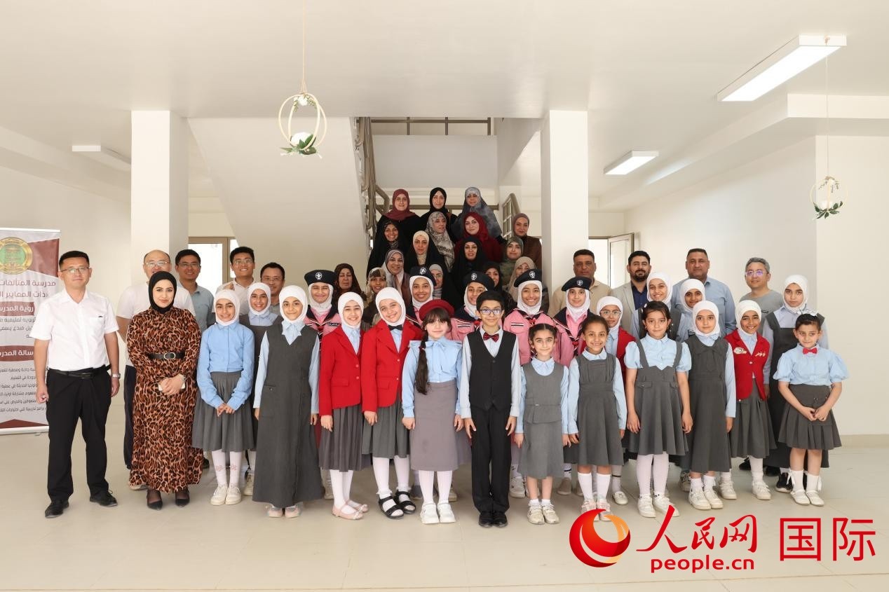 中國(guó)電建員工與阿爾穆塔?阿里卡特國(guó)際學(xué)校的師生及政府官員等合影。人民網(wǎng)記者 薛丹攝