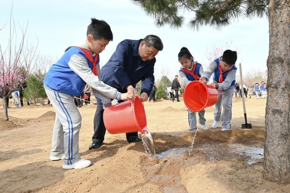 2025年4月3日，習(xí)近平總書記等來到北京市豐臺區(qū)永定河畔參加首都義務(wù)植樹活動。這是習(xí)近平總書記同少先隊員一起給剛栽下的樹苗澆水。新華社記者 謝環(huán)馳 攝